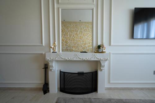 a fireplace in a white room with a mirror above it at Paris-Oasis Casablanca avec piscine panoramique in Casablanca