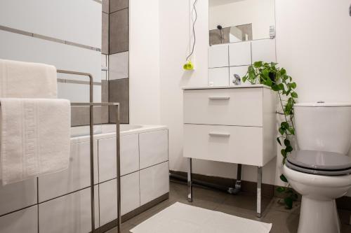 La salle de bains blanche est pourvue de toilettes et d'une baignoire. dans l'établissement Au coeur de Perpignan, à Perpignan