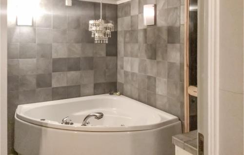 - Baño con bañera blanca y pared de azulejos en Gorgeous Home In Sk With Kitchen en Skå