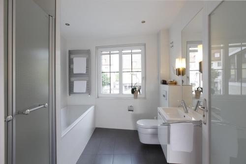 a white bathroom with a toilet and a sink at Hotel Warteck in Freudenstadt