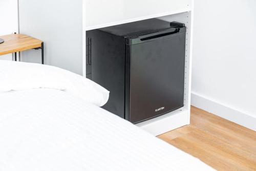 Cette chambre comprend un lit et un réfrigérateur noir. dans l'établissement Calme & Chic vert - Proche gare et centre, à Dijon