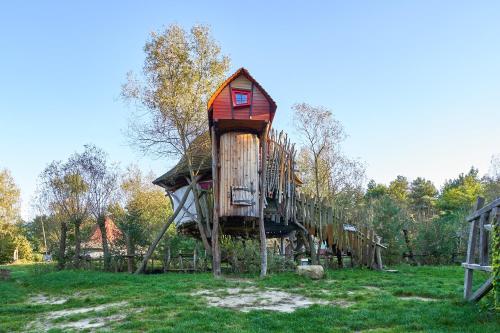 una casa en un árbol con un tobogán en un campo en Baumhaushotel - Die geheime Welt von Turisede - Kulturinsel Einsiedel, en Zentendorf