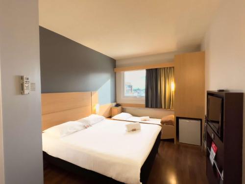 een hotelkamer met 2 bedden en een televisie bij ibis Passo Fundo Centro in Passo Fundo