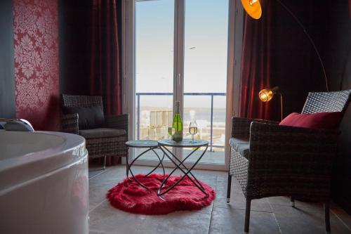 baño con bañera, mesa y ventana en Hôtel L'Embarcadère, en La Barre-de-Monts