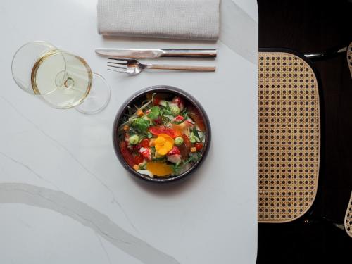 a bowl of salad on a table with a glass of wine at Hôtel LÉONOR the place to live in Strasbourg