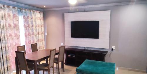 a dining room with a table and a flat screen tv at Labas Travellers Guesthouse in Jozini