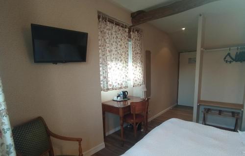a hotel room with a desk and a television on the wall at Logis Auberge le centre poitou in Coulombiers