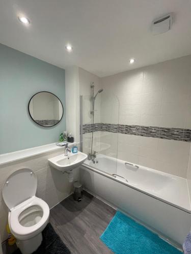 a bathroom with a toilet and a tub and a sink at Balcony Marina Apartment With City Skyline Views in Manchester
