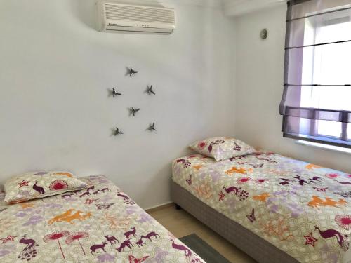 ケメルにあるAttolos Residenceの蝶が壁に描かれたベッドルーム内のベッド2台