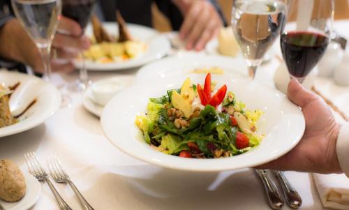 a person holding a plate of food on a table at Dekelia Hotel in Athens