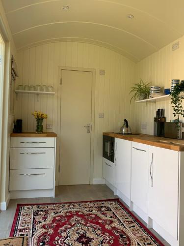 a kitchen with white cabinets and a red rug at The City Hut in Bath