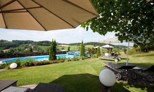 un giardino con ombrellone e piscina di Maiers Kuschelhotel Loipersdorf Deluxe - ADULTS ONLY a Loipersdorf bei Fürstenfeld