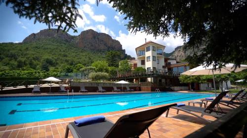 a swimming pool with chairs and a building in the background at Hotel Can Boix de Peramola in Peramola