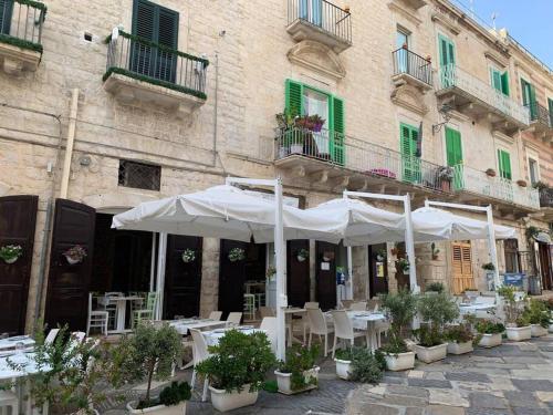 焦維納佐的住宿－Casa Vacanza Raggio di sole，大楼前的室外咖啡厅,配有桌子和白色遮阳伞