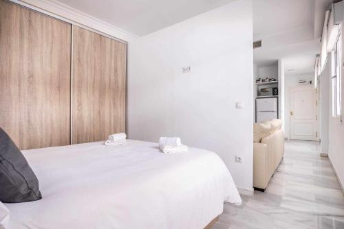 biała sypialnia z dużym białym łóżkiem i drewnianymi szafkami w obiekcie COMFY AWAY - Apartamento Deluxe Centro Histórico w Sewilli