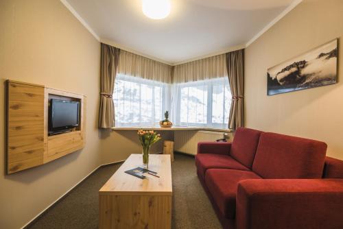 a living room filled with furniture and a tv at Horsky Hotel Sliezsky Dom in Vysoké Tatry