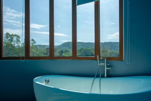 a bath tub in a room with windows at Phurua Sanctuary Resort and Spa in Phu Ruea