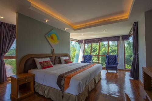 um quarto com uma cama grande e algumas janelas em Phurua Sanctuary Resort and Spa em Phu Rua