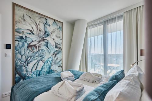 1 dormitorio con 1 cama con una pintura en la pared en Wave - Gold Suite Sea View, en Międzyzdroje
