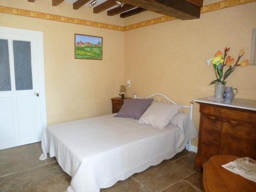 1 dormitorio con 1 cama y un jarrón de flores en Gîte du Charmoy en Clomot