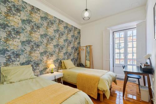 a bedroom with two beds and a desk and a window at A Casa Amarela de Sintra in Sintra