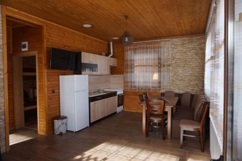 een keuken met een tafel en een witte koelkast bij Ваканционно селище Ива in Sarnitsa