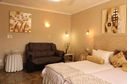 una habitación de hotel con 2 camas y una silla en Villa Ticino Guest House en Sabie