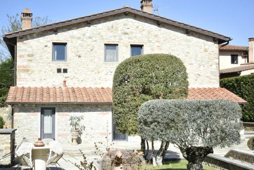 a stone house with a large bush in front of it at Appartamento in Villa con Piscina - Mhateria Relais in Rignano sullʼArno