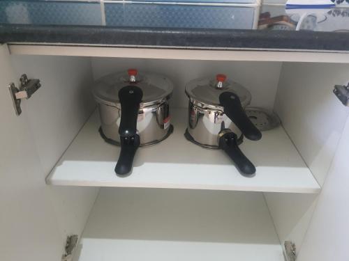 two pots and pans sitting on a shelf in a kitchen at Castle Dollars in Bengaluru