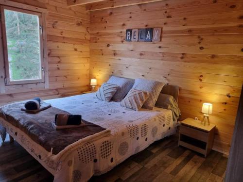 een slaapkamer met een bed in een blokhut bij Cabane pilotis sur étang, au lac de Chaumeçon in Saint-Martin-du-Puy