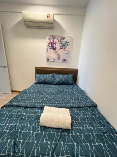 Un dormitorio con una cama azul con una toalla. en SNHomestay1826 Sea View @ The Wave Residence en Melaka