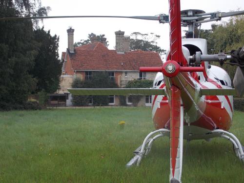 a red and white helicopter parked in a field at Rectory Manor in Lavenham
