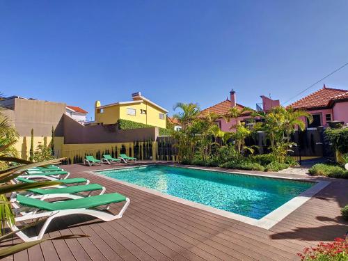 a swimming pool with chaise lounge chairs next to a house at Sunlight Apartment by LovelyStay in Funchal