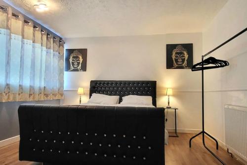 een slaapkamer met een bed en een zwarte bank bij Cosy 3 double bed flat sleeps 6 in Bedworth