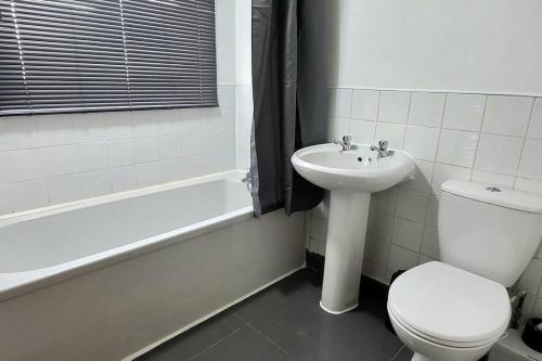 een badkamer met een toilet, een wastafel en een bad bij Cosy 3 double bed flat sleeps 6 in Bedworth
