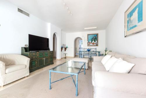 Il comprend un salon doté d'un mobilier blanc et d'une télévision à écran plat. dans l'établissement Apartamento Guadalmina Golf l, à Marbella