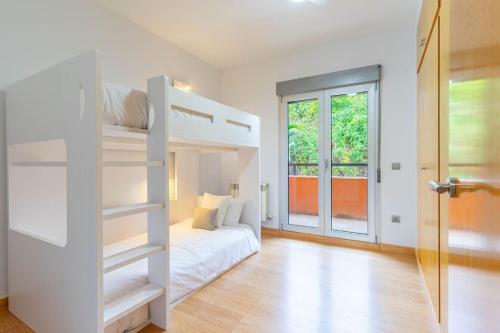 a white bedroom with a bunk bed and a door at Acogedora Villa en Alicante capital con barbacoa in Alicante