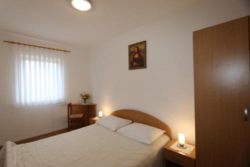 sypialnia z białym łóżkiem z 2 świecami w obiekcie Apartments Znidarec w mieście Šilo