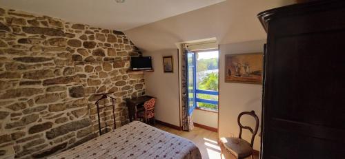 a bedroom with a stone wall with a bed and a window at Auberge De Bel Air in Brélès