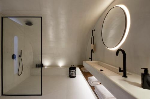 a bathroom with a tub and a sink and a mirror at U & ME SUITES in Fira