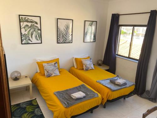 two beds in a room with yellow sheets at Casa Luana - Rooms in Sagres