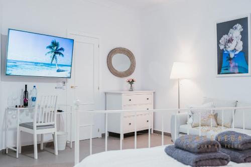 a white bedroom with a white bed and a white desk at Vv CONDEVEGA in Telde