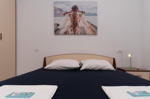 a bed with two pillows and a picture of a woman at Joseph - superior sea bay and mountain view in Cavtat