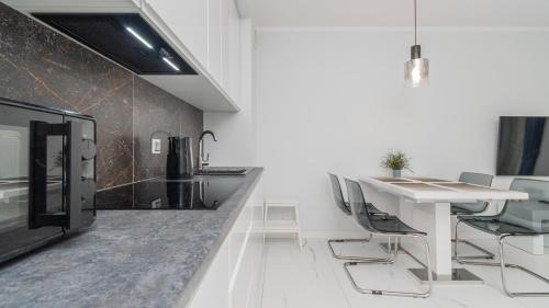 a white kitchen with a white table and chairs at Bursztynowe Osiedle Jantar, Sun & Snow in Jantar