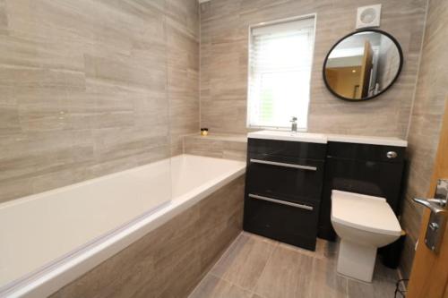 a bathroom with a tub and a toilet and a mirror at The Cottage IH3ATL in Stockton-on-Tees