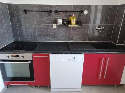 une cuisine avec des armoires rouges et un comptoir noir dans l'établissement Spacieux appartement residence securisee, garage, à Marseille