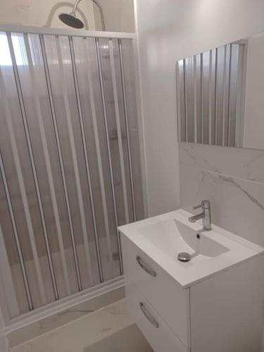 une salle de bain blanche avec une douche et un lavabo dans l'établissement Spacieux appartement residence securisee, garage, à Marseille