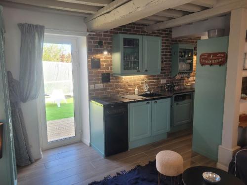 a kitchen with blue cabinets and a brick wall at Domaine "Les Bois Flottes" dans Maison de Charme au bord de mer et proche de Cabourg in Merville-Franceville-Plage