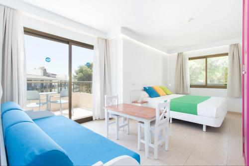a room with a bed and a table and a couch at Guya Wave Hotel in Cala Ratjada