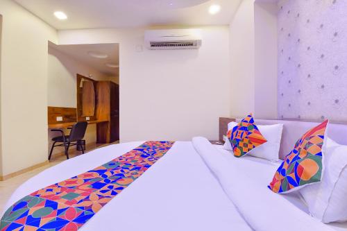 a bedroom with a large white bed with colorful pillows at FabHotel Hill Park in Ahmedabad